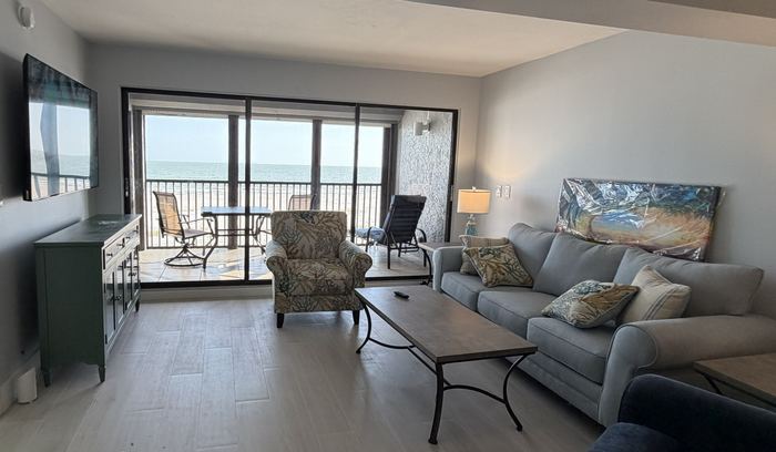 Living room with sliding doors open to the screened lanai and the Gulf beyond
