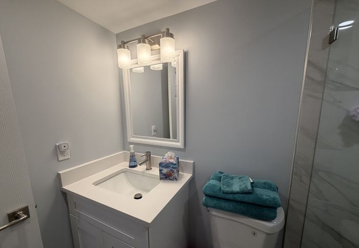 Remodeled bathroom vanity with quartz top beside the walk in shower