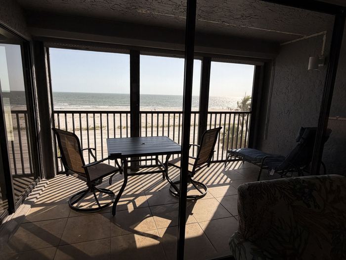Screened lanai with dining table looking out over the beach