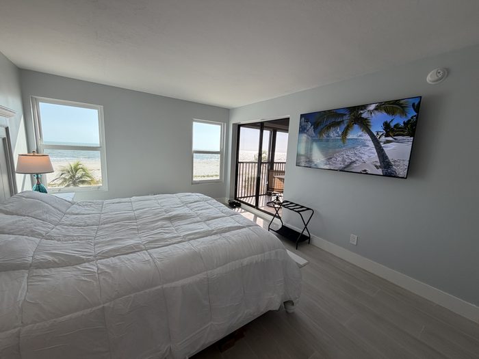Primary bedroom with king bed, 65 inch smart TV and private lanai door looking out to the Gulf