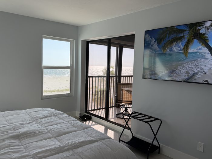 Primary bedroom sliding door opening onto the screened lanai above the beach