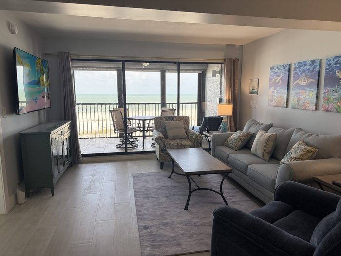 Screened lanai set with a table and four chairs, looking out over the beach to the Gulf