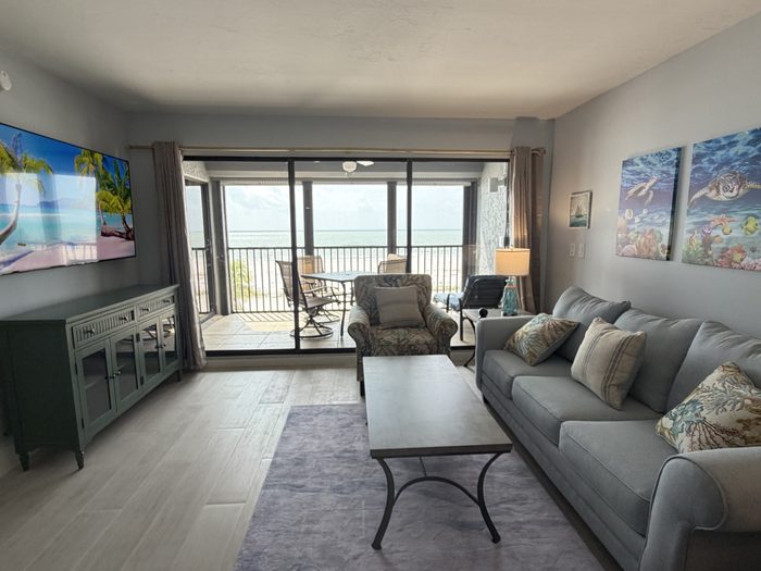 Living room opening onto the screened lanai with four chairs and the Gulf beyond