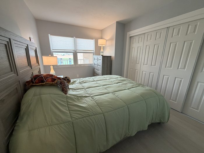 Guest bedroom with queen bed, closet storage and a window to the beach