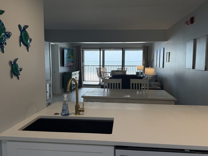 Kitchen sink and breakfast bar with decorative turtles on the wall, looking through to the lanai and the Gulf
